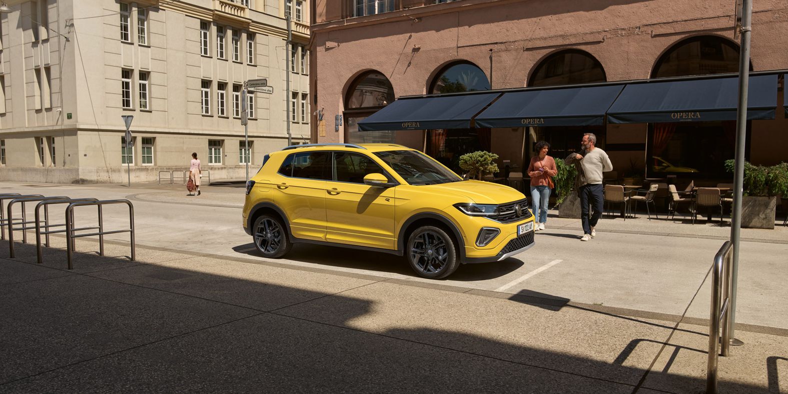 Ein geparkter T-Cross am Straßenrand, auf den 2 Personen von der anderen Straßenseite zugehen