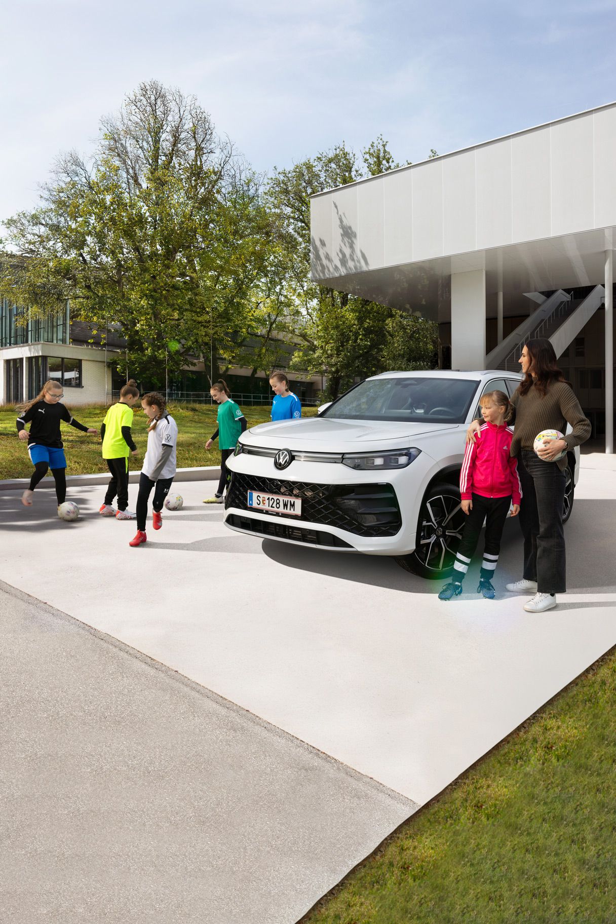 Frau und Kinder spielen in einer Einfahrt vor dem neuen Tayron Fußball