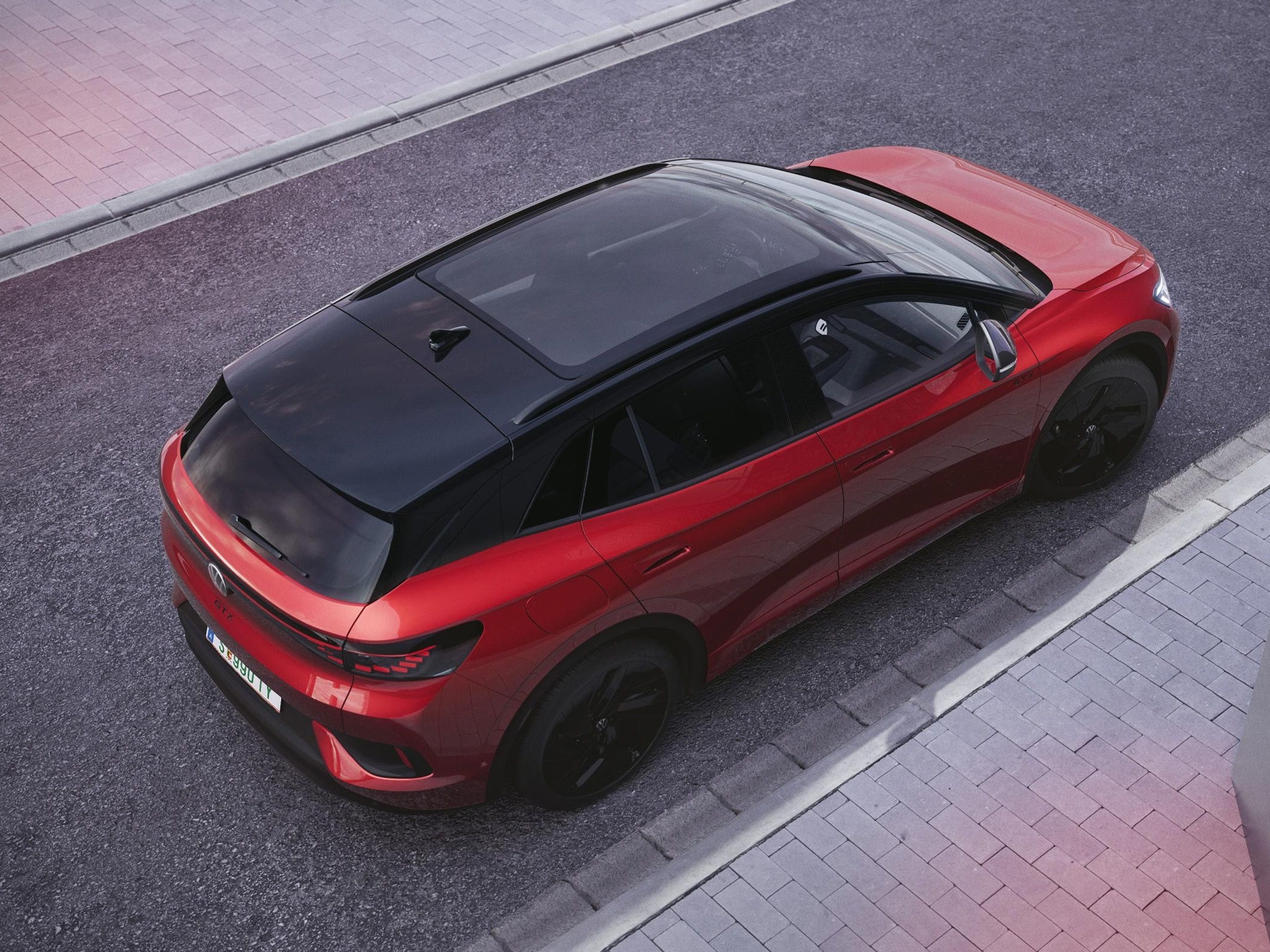 Ansicht aus der schräg rechten Vogelperspektive auf einen roten VW ID.4 GTX, der auf einer Straße steht.