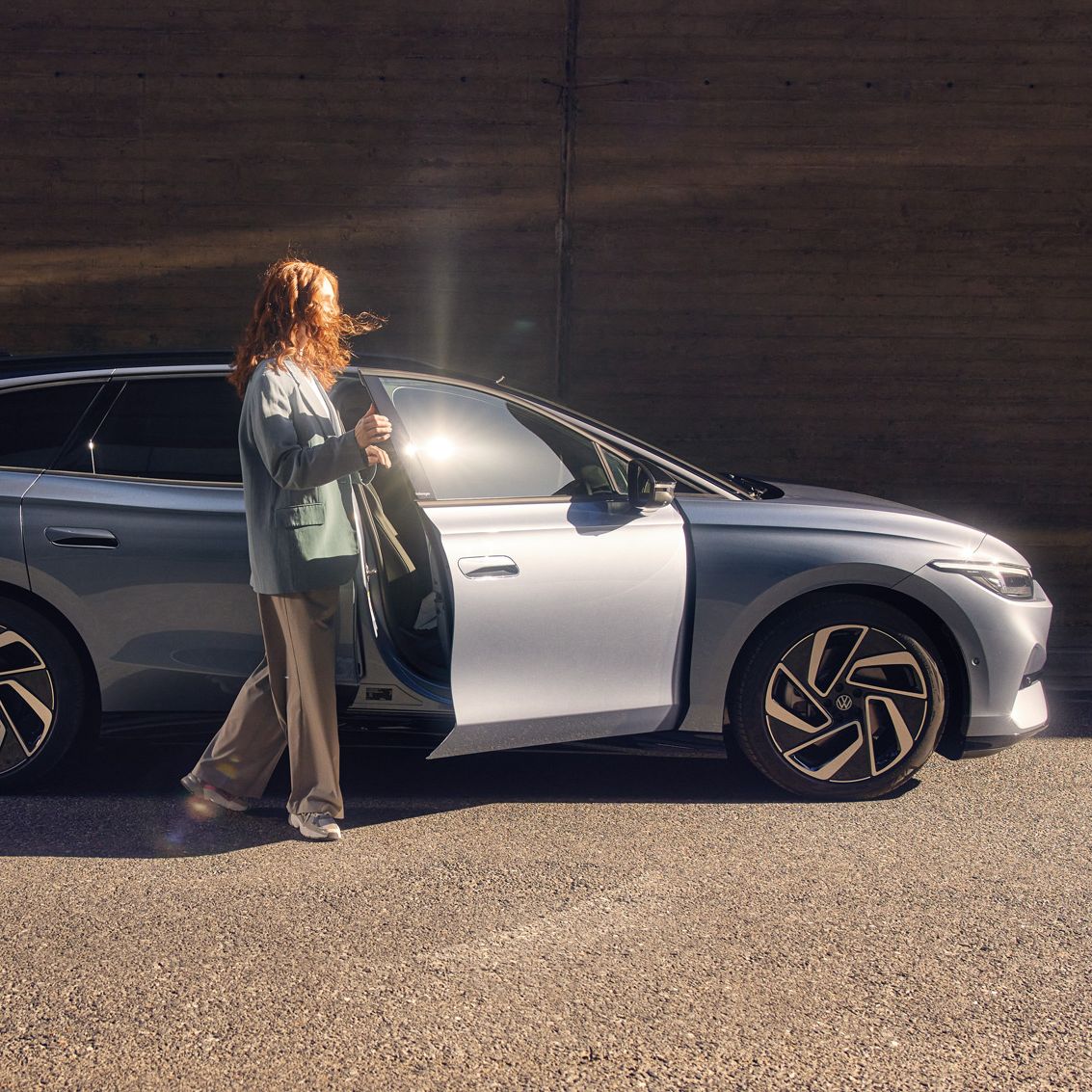 Eine Frau steht vor der geöffneten Beifahrertüre eines ID.7 Tourer 