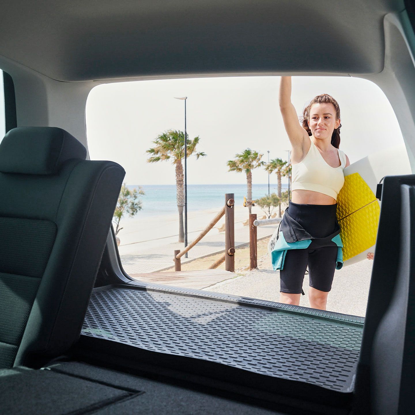 Blick durch das Heck eines Volkswagen Golf Sportsvan. Eine Frau schließt die Heckklappe.