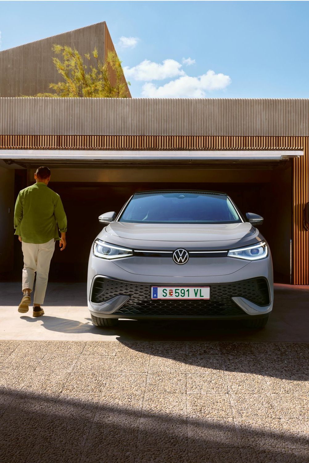 ID. steht vor der Garage und ein Mann geht seitlich vorbei 