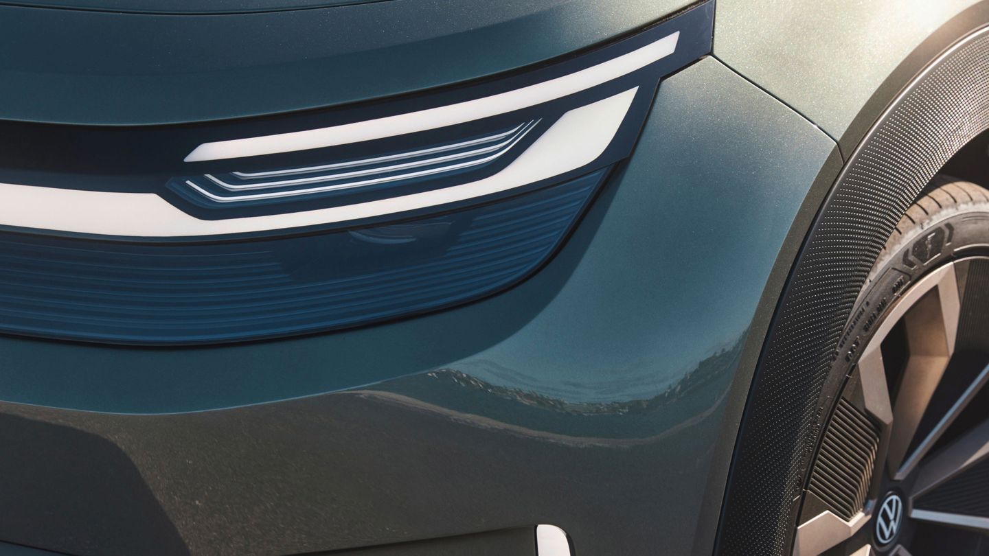 Nahaufnahme eines Autoscheinwerfers und eines Teils des Radkastens von einem modernen Fahrzeug. Der Scheinwerfer hat ein stylisches, geschwungenes LED-Design. Teile der Metallkarosserie sind ebenfalls sichtbar.