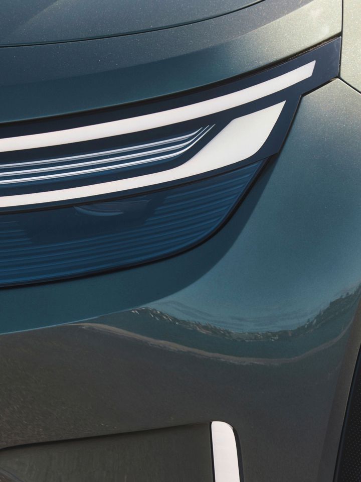 Nahaufnahme eines Autoscheinwerfers und eines Teils des Radkastens von einem modernen Fahrzeug. Der Scheinwerfer hat ein stylisches, geschwungenes LED-Design. Teile der Metallkarosserie sind ebenfalls sichtbar.