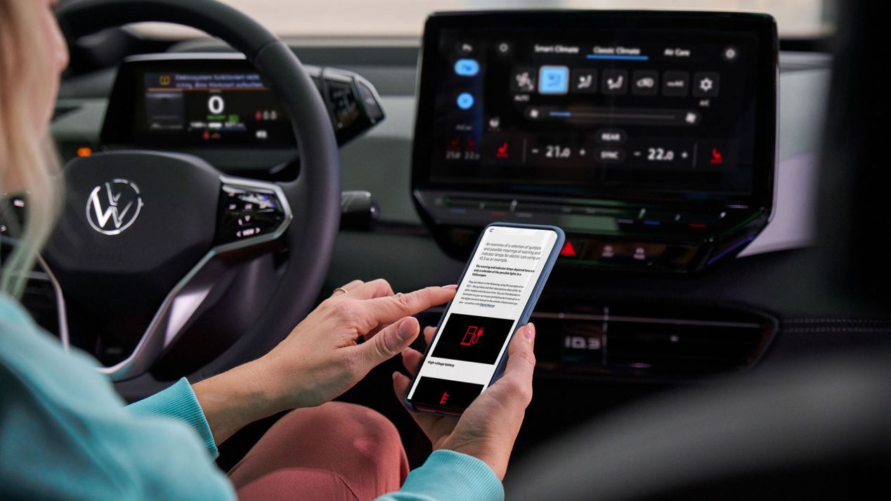 Kundin sitzt am Lenkrad eines VW-Autos und informiert sich über Warnleuchten
