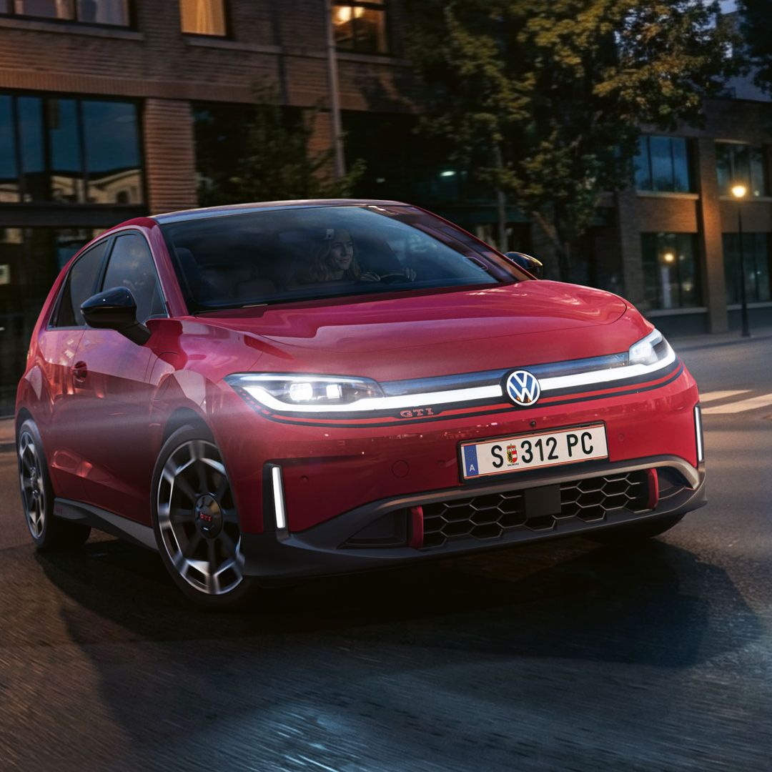 Ein roter VW ID. Polo GTI biegt bei abendlicher Stimmung in eine Straße ein.