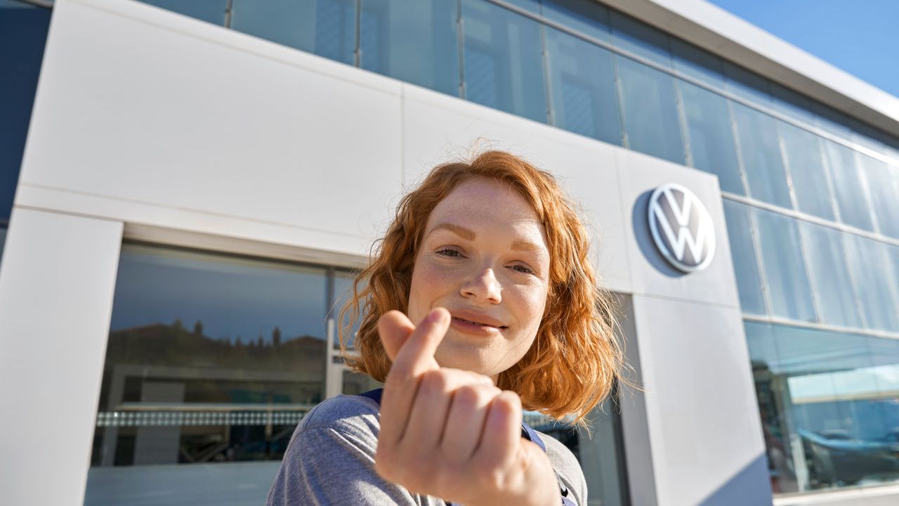 Volkswagen Service Mitarbeiterin vor dem Eingang zu einem Volkswagen Service Partner