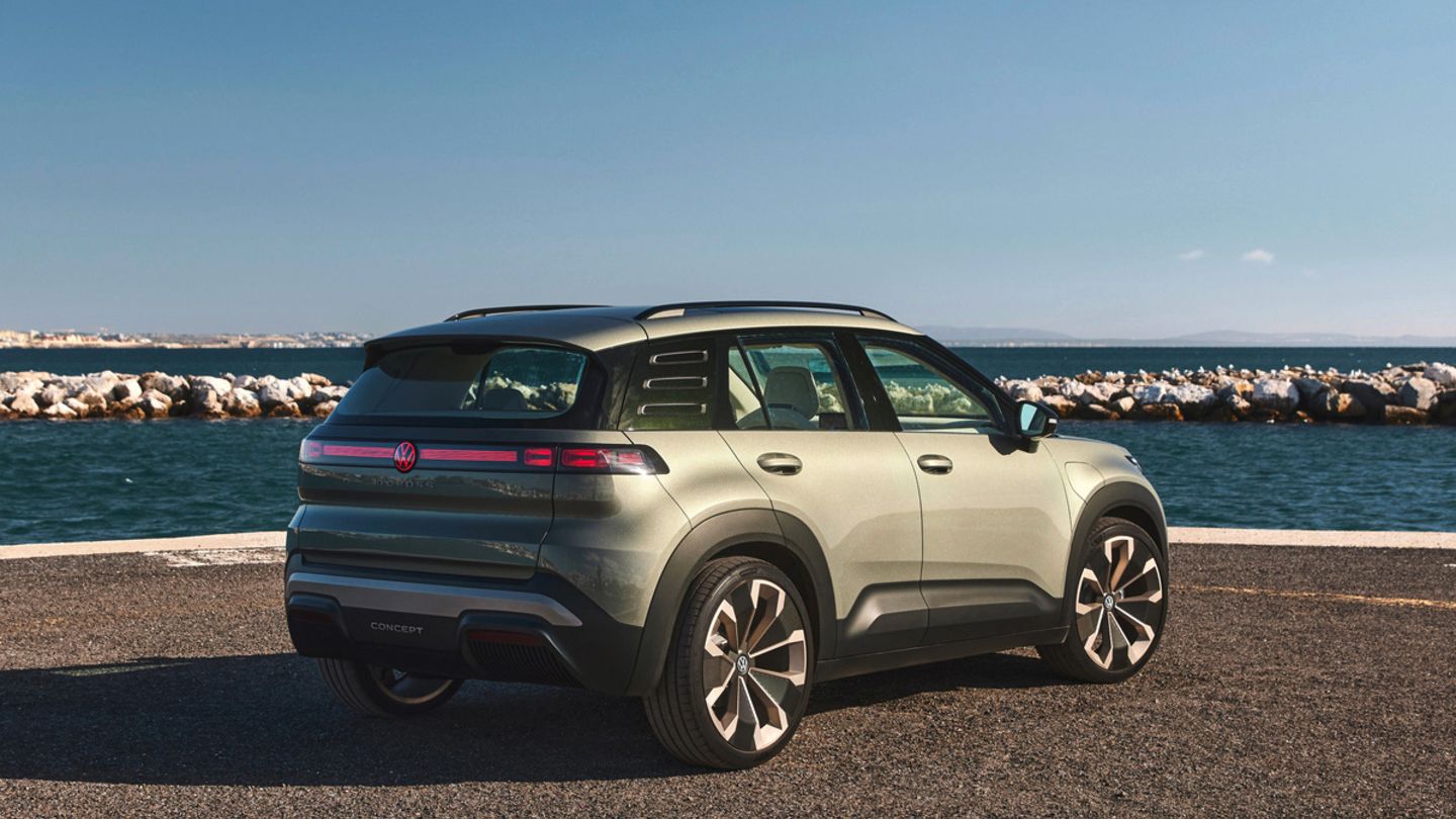 Ein grüner VW ID. Cross steht auf einer Küstenstraße mit Blick auf das Meer und einen blauen Himmel ohne Wolken. Im Hintergrund sind Felsen zu sehen, die das Meer abgrenzen.