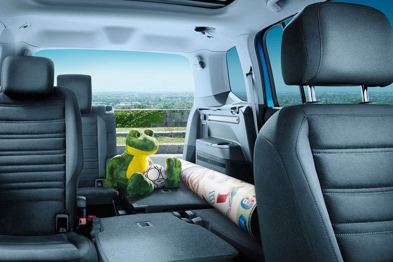 Umgeklappte Rücksitzbänke des VW Touran, ein eingerollter Teppich und ein Froschkuscheltier liegen auf der freien Fläche. 