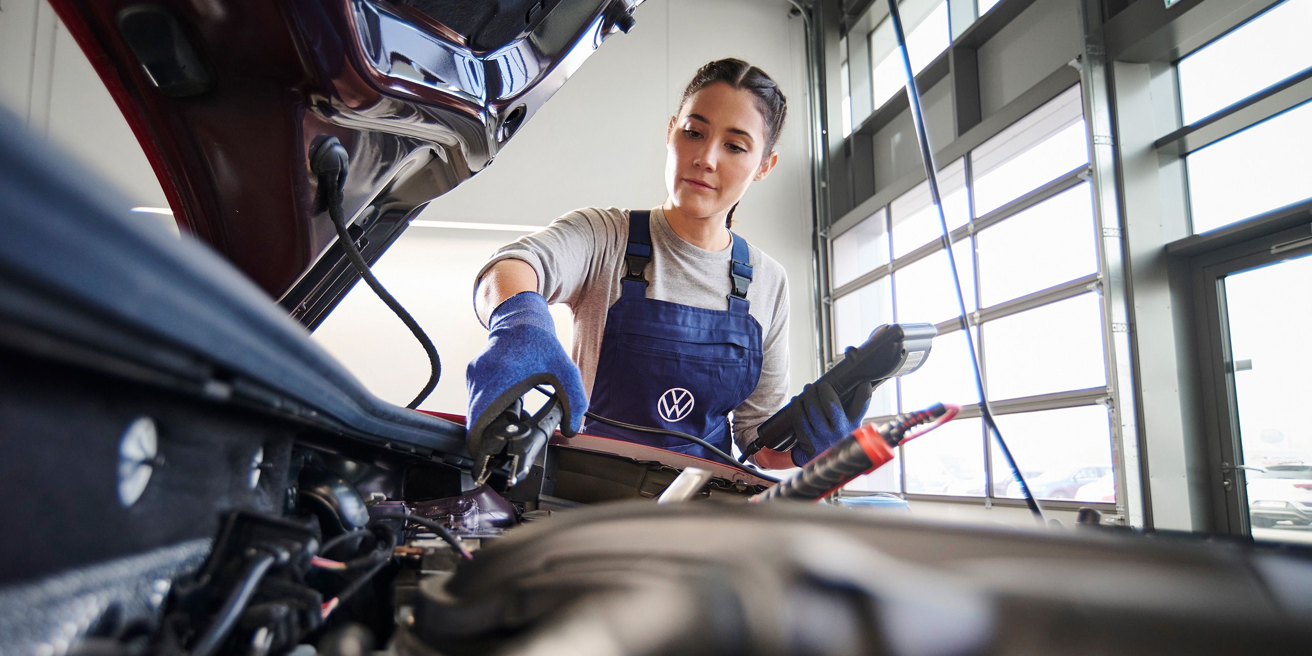 Eine Volkswagen Mechanikerin beim Funktionstest der Starterbatterie.