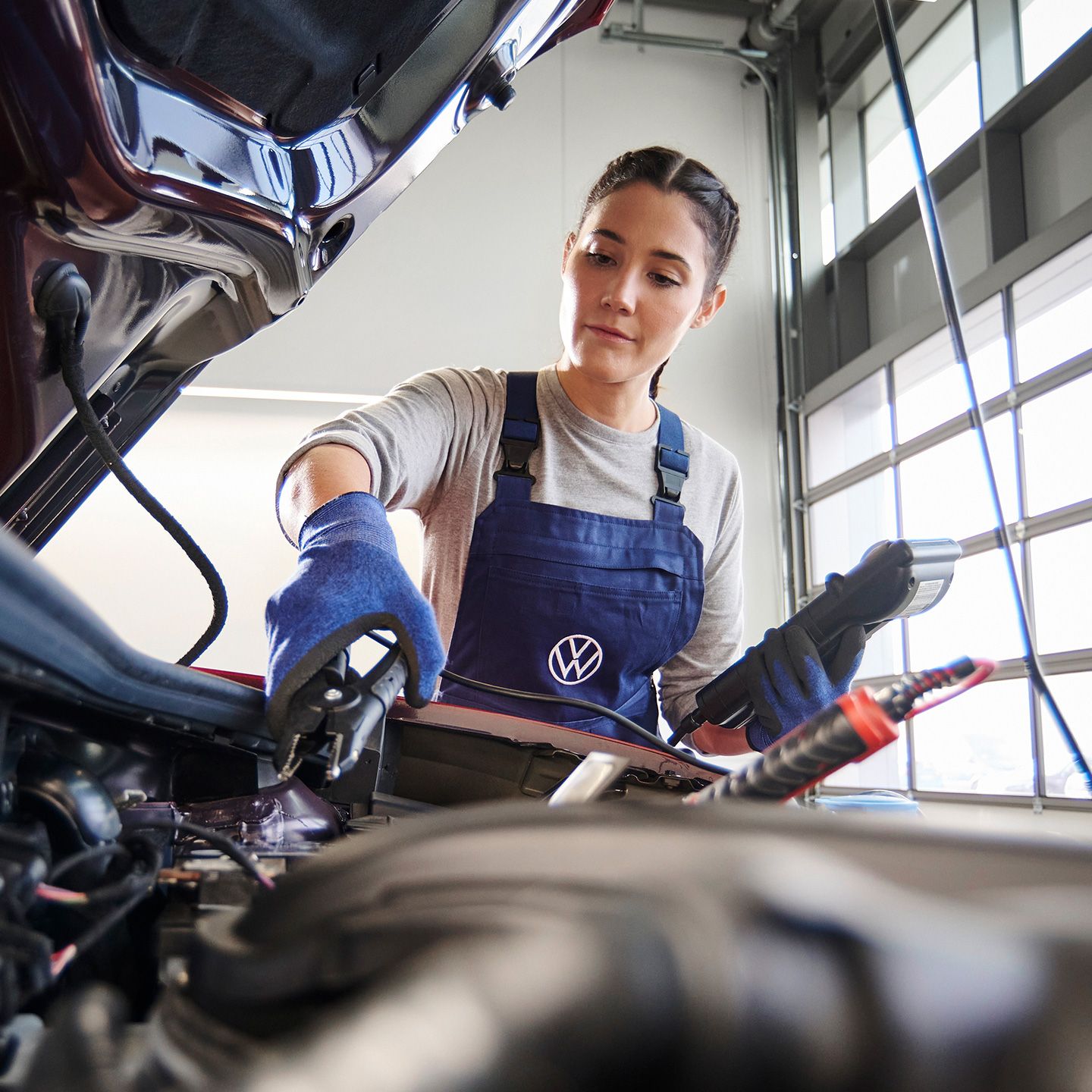 Eine Volkswagen Mechanikerin beim Funktionstest der Starterbatterie.
