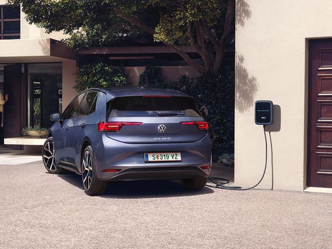 Ein blauer VW ID.3 Neo lädt an einer Wallbox vor einem Einfamilienhaus