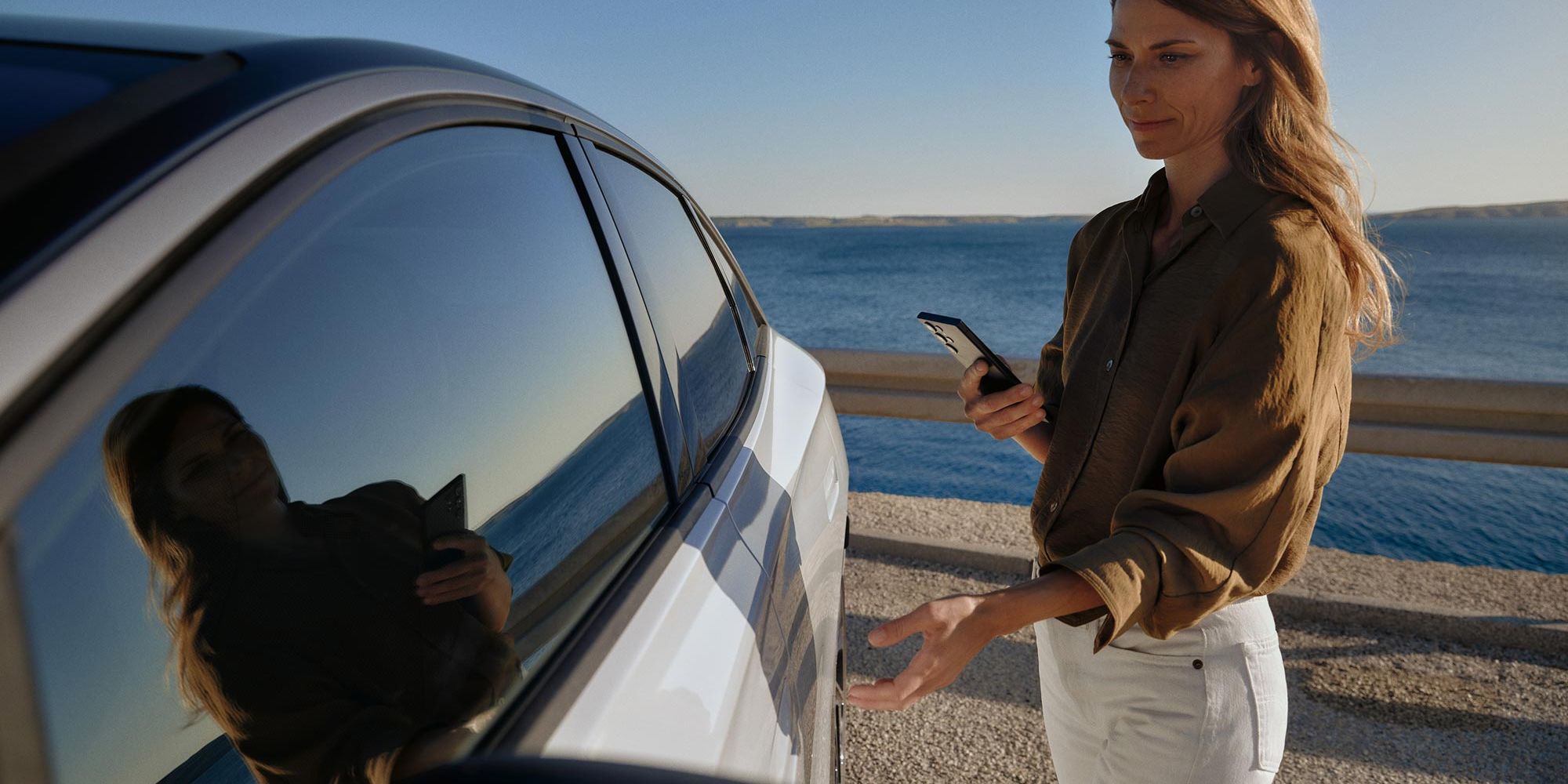 Eine Frau geht zu einem weißen VW ID.7 und öffnet die Tür. 
