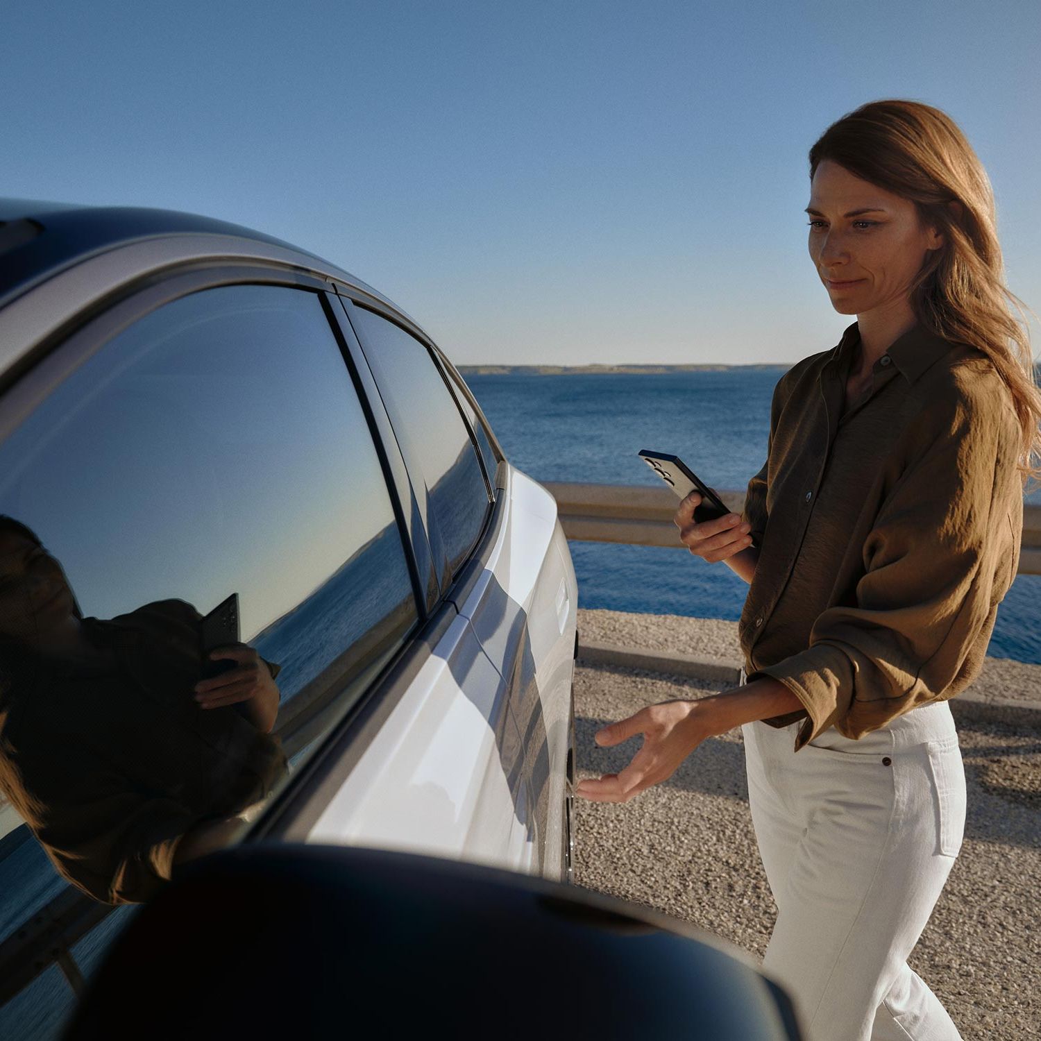 Eine Frau geht zu einem weißen VW ID.7 und öffnet die Tür. 