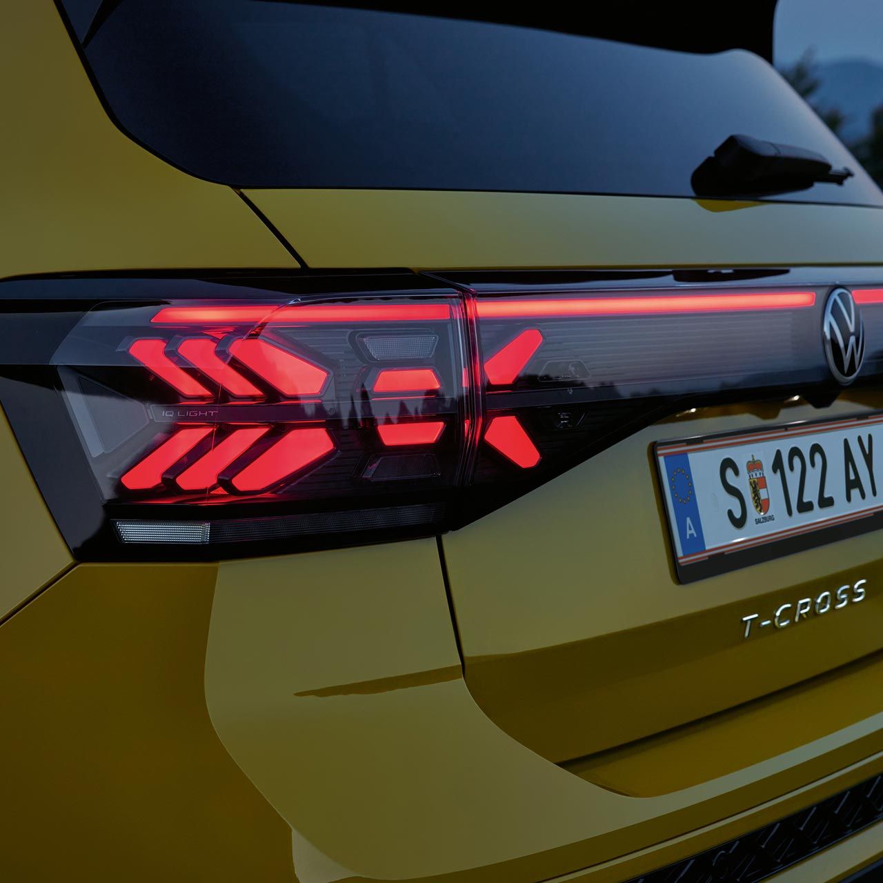 IQ. LIGHT Rückbeleuchtung eines gelben VW T-Cross in Großaufnahme in der Dämmerung.