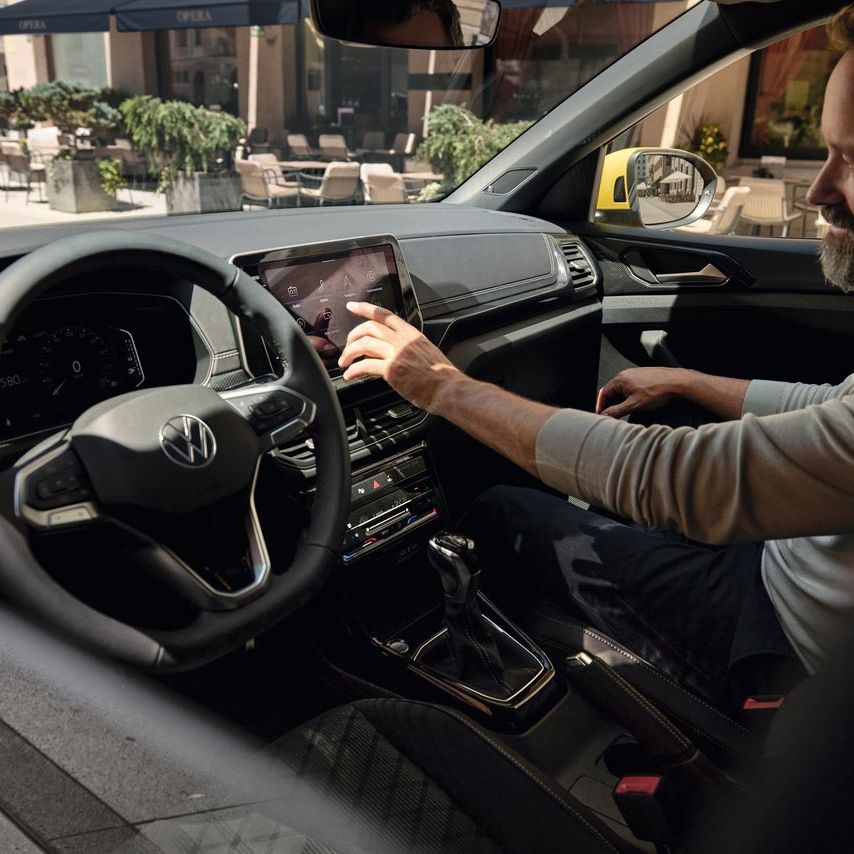 Ein Mann bedient vom Beifahrersitz aus den Bildschirm des VW T-Cross