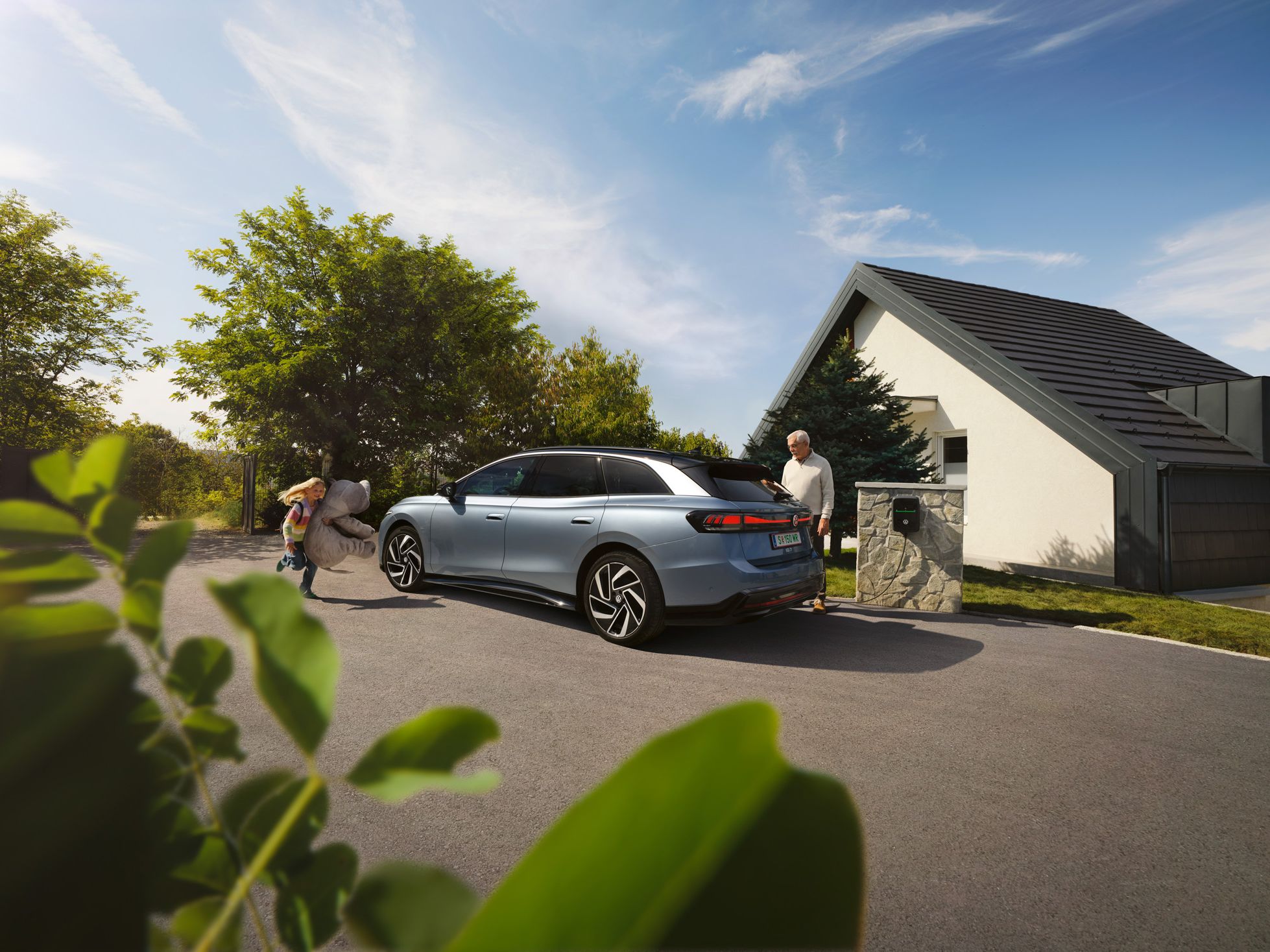 Ein VW ID.7 Tourer parkt vor einem Haus und wird am ID. Charger 2 geladen.