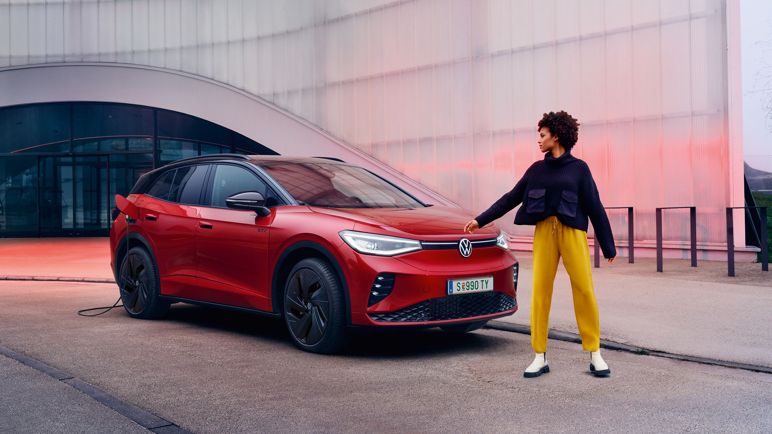 Frau steht vor rotem ID.4 GTX 4MOTION, der gerade geladen wird