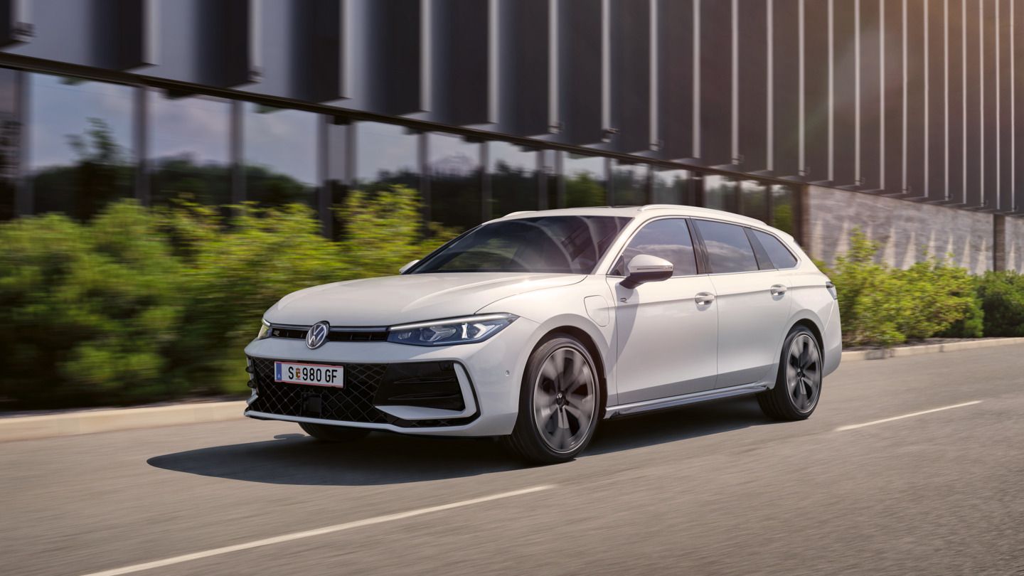 Ein weißer VW Passat fährt vor einem modernen Bürogebäude entlang.