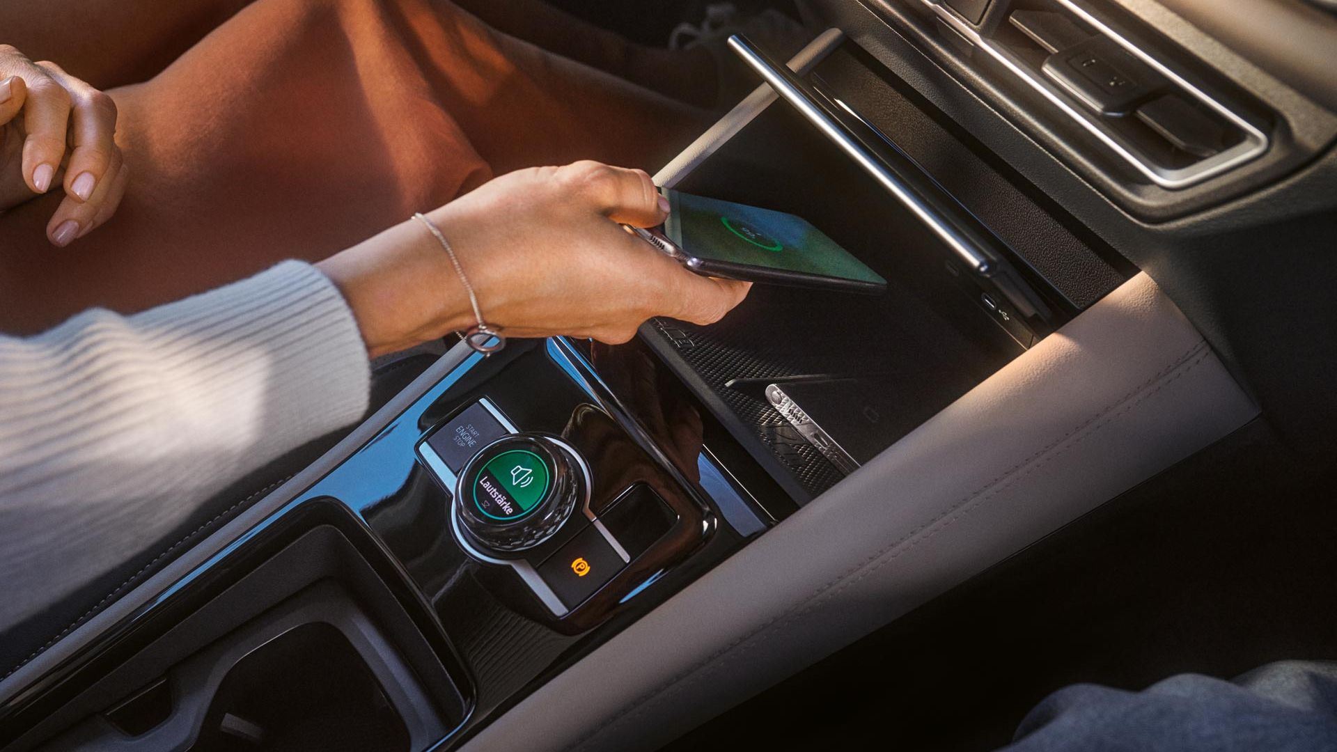 Person legt Smartphone in Ablage für Wireless Charging im VW Tiguan