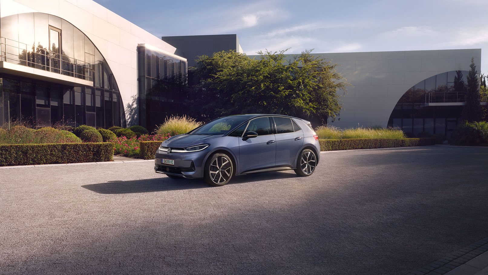 Ein blauer VW ID.3 Neo parkt vor einem modernen Gebäude