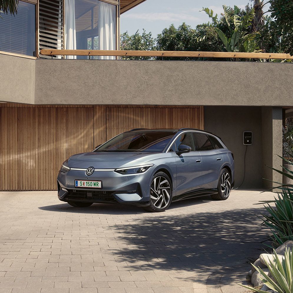 ID.7 Tourer steht geparkt vor einem modernen Haus in einer Einfahrt in Frontansicht. 