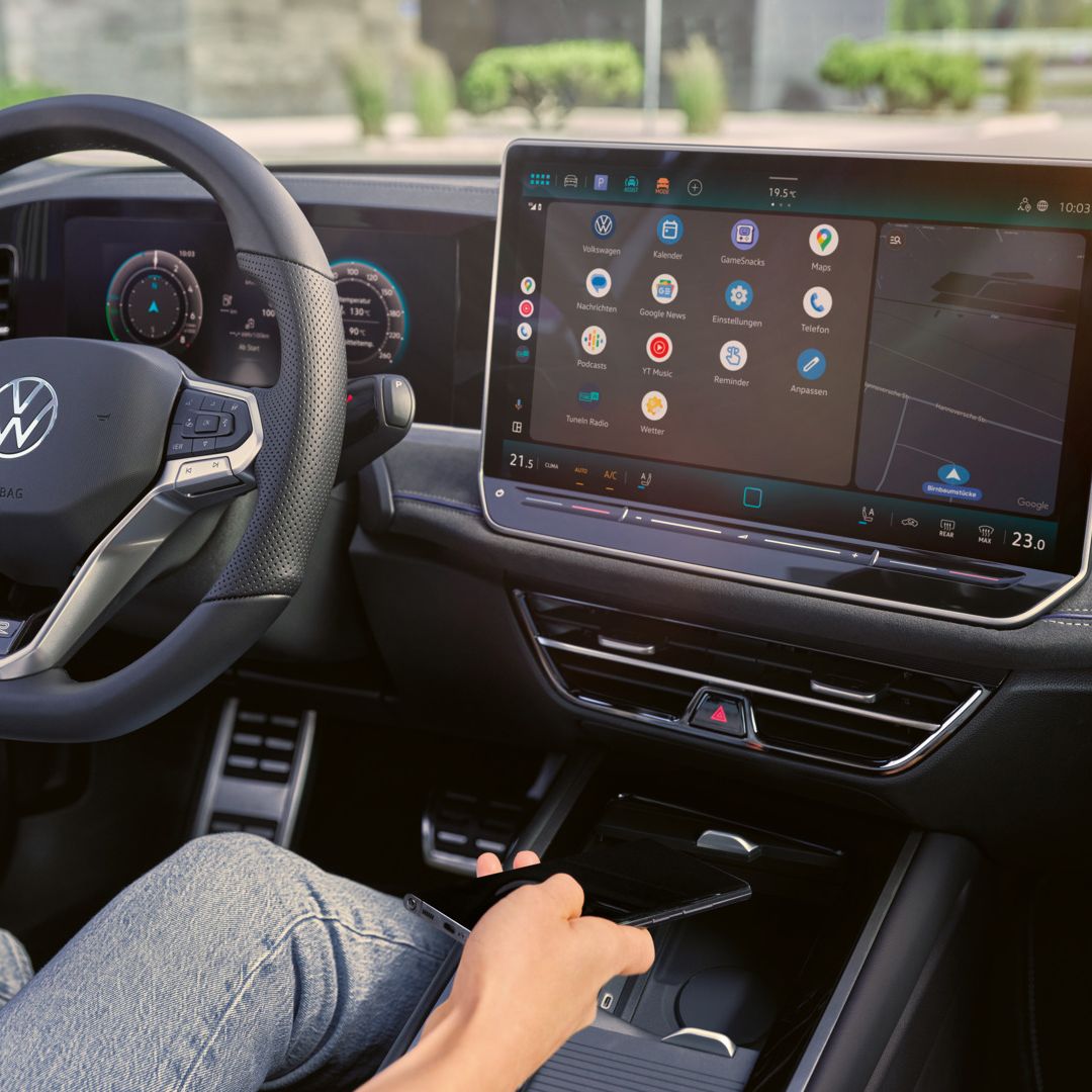 Detailansicht auf das Cockpit des VW Passast. Eine Person auf dem Fahrersitz hält ein Smartphone in der Hand.