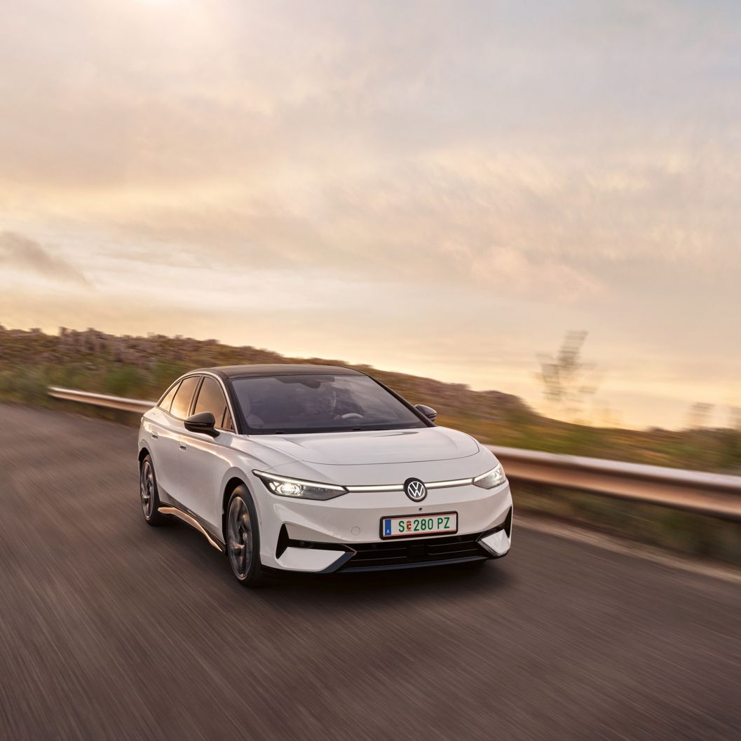 Blick auf die aerodynamisch gestaltete Front eines weißen VW ID.7, der auf einer Landstraße fährt.