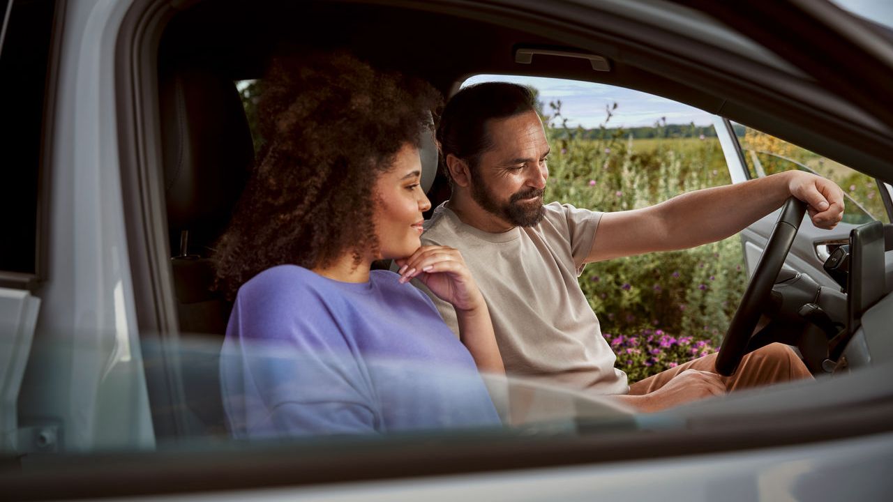 Paar in ihrem Volkswagen blicken aufs Display