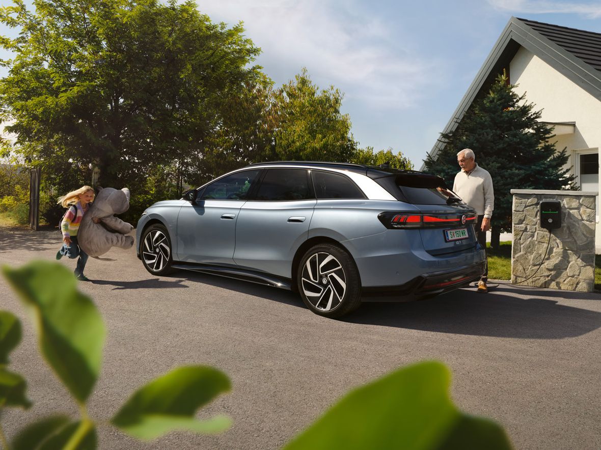 Ein VW ID.7 Tourer parkt vor einem Haus und wird am ID. Charger 2 geladen.