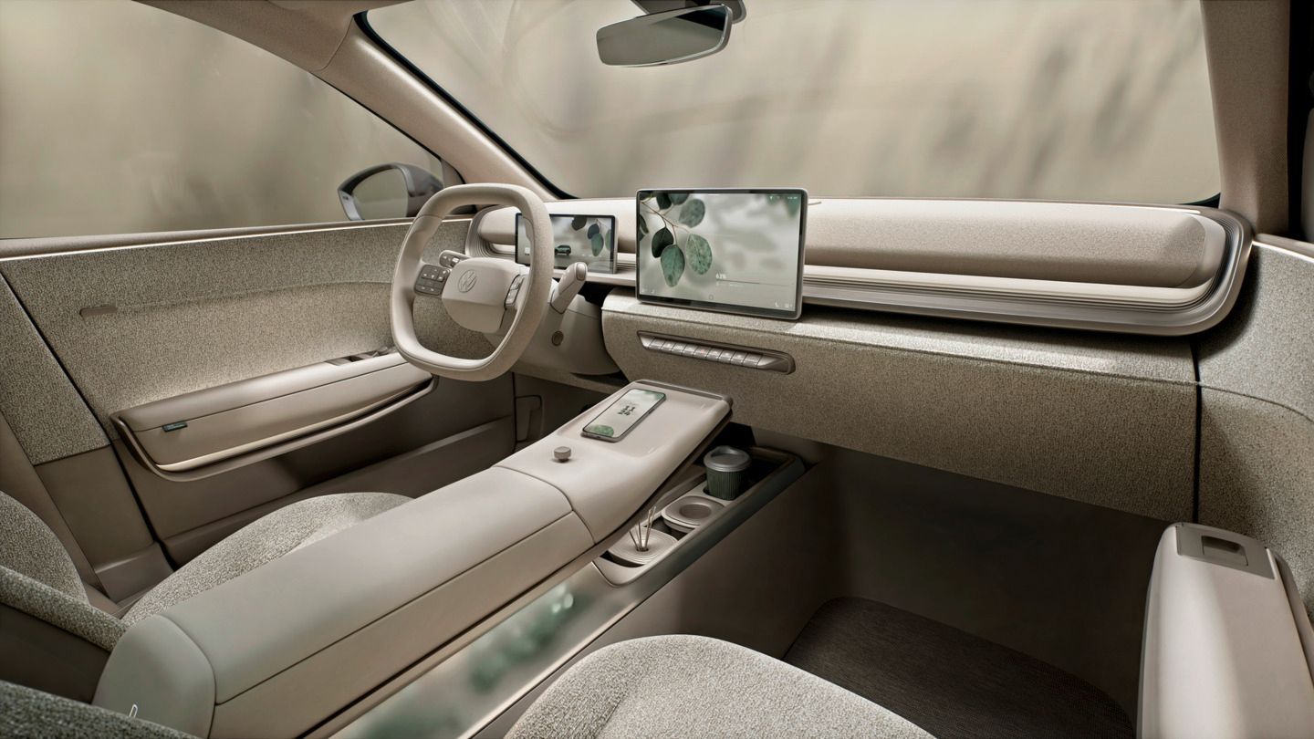 Bild des vorderen Interieurs vom VW ID Cross Concept. Aus der Perspektive des Beifahrersitzes sieht man das den Fahrersitz, die Mittelkonsole, das Infotainment, Lenkrad und Frontscheibe. Alles im Interieur ist in beige gehalten.