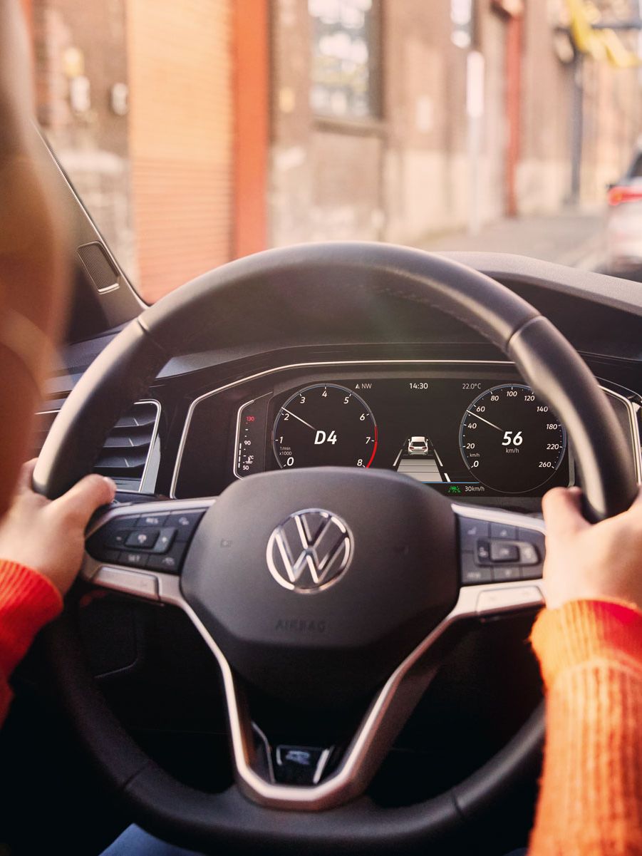 Eine Frau fährt einen VW Polo mit aktiver Navigation auf dem Display des Infotainment-Systems.