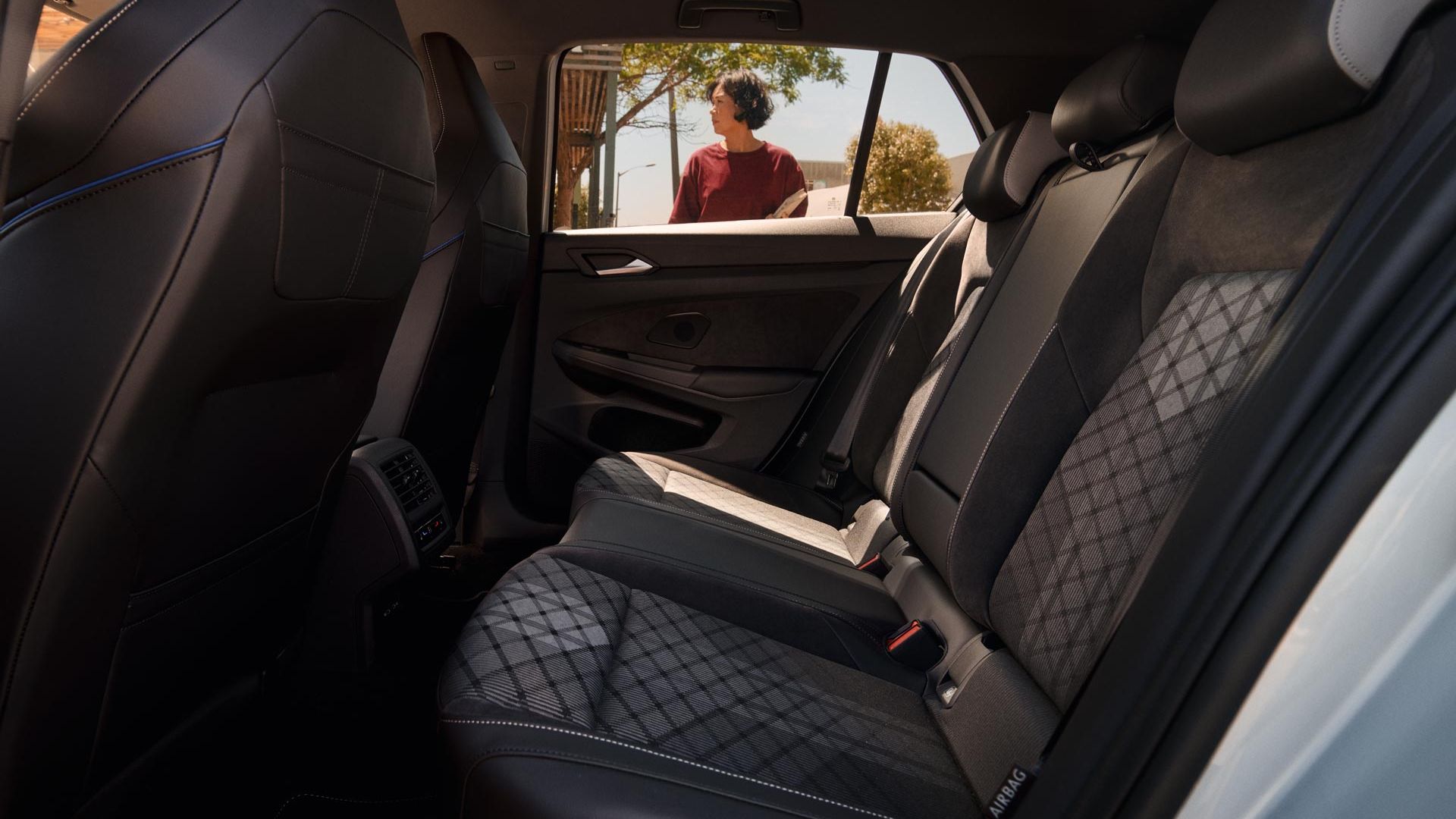 Ansicht einer Rücksitzbank eines VW Golf R-Line, durch das Fenster sieht man eine Frau