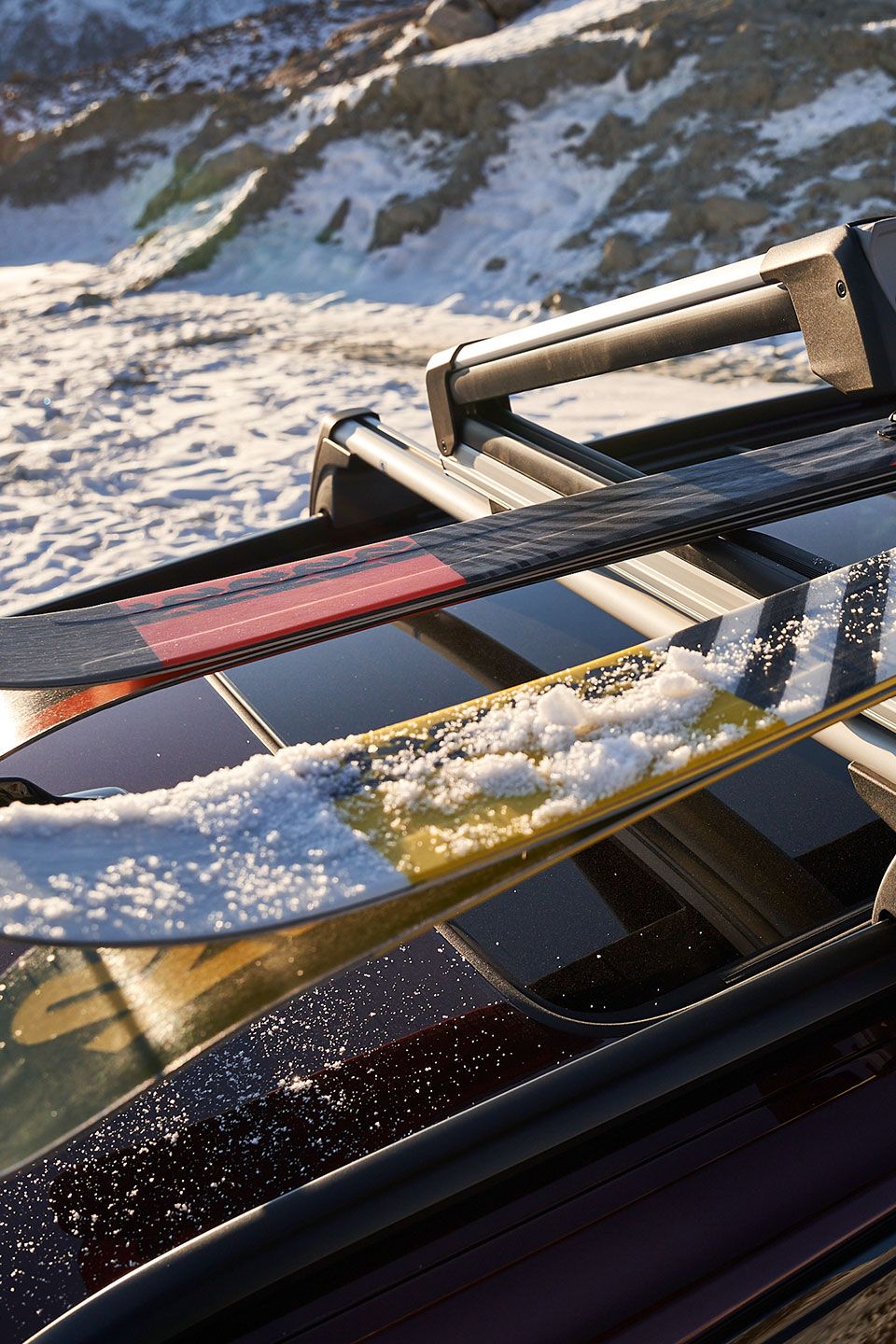 Am Skidachträger auf dem Dach eines Volkswagen werden zwei paar Ski befestigt.