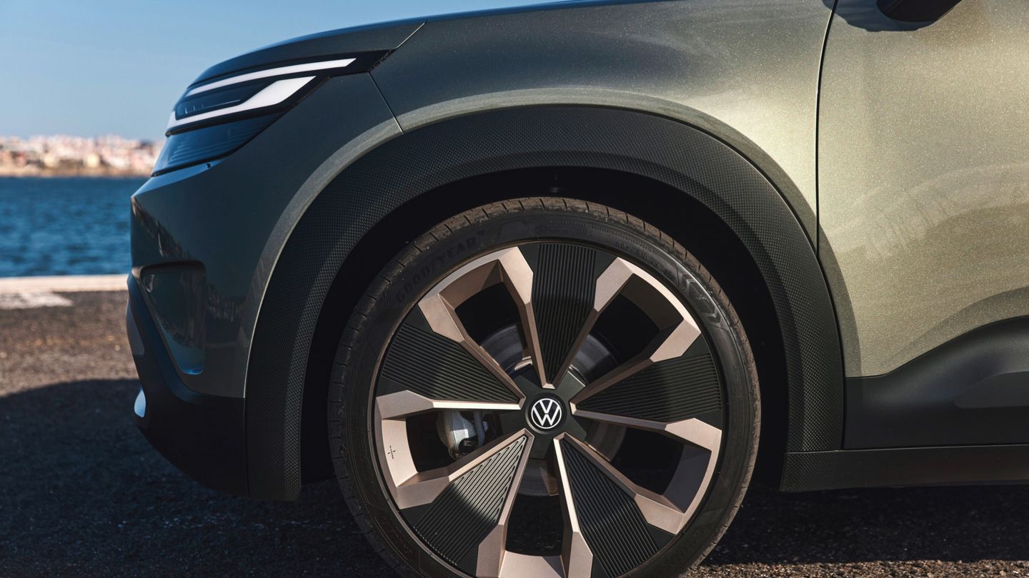 Nahaufnahme des vorderen rechten Radbereichs eines Volkswagen Elektroautos. Das Rad hat ein modernes, stylisches Design und der Hintergrund zeigt einen Wasserblick und einen klaren Himmel.