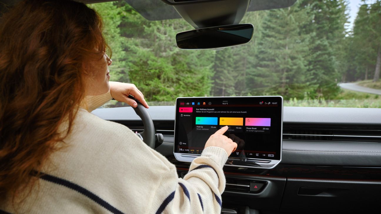 Eine Frau wählt am Touchscreen ein Wellnessprogramm im VW ID.7 aus.