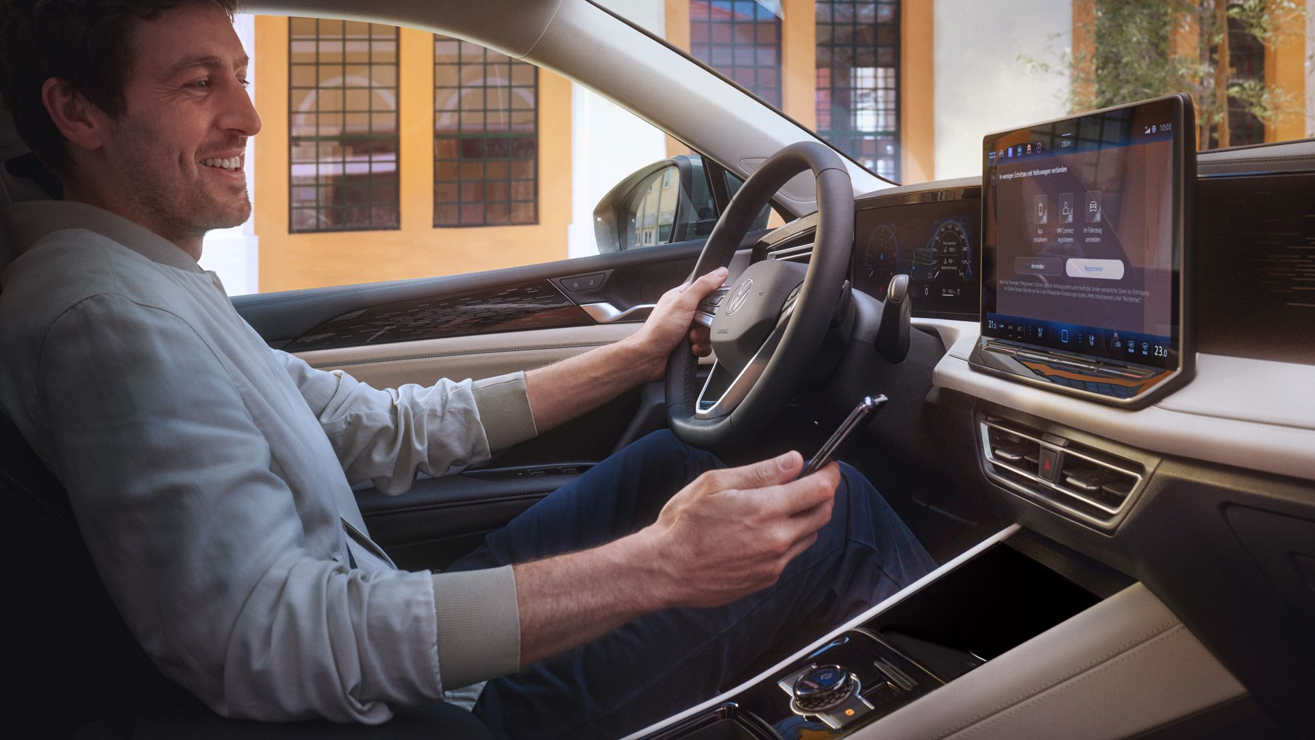 Mann sitzt in VW Tiguan und hält Smartphone in der Hand