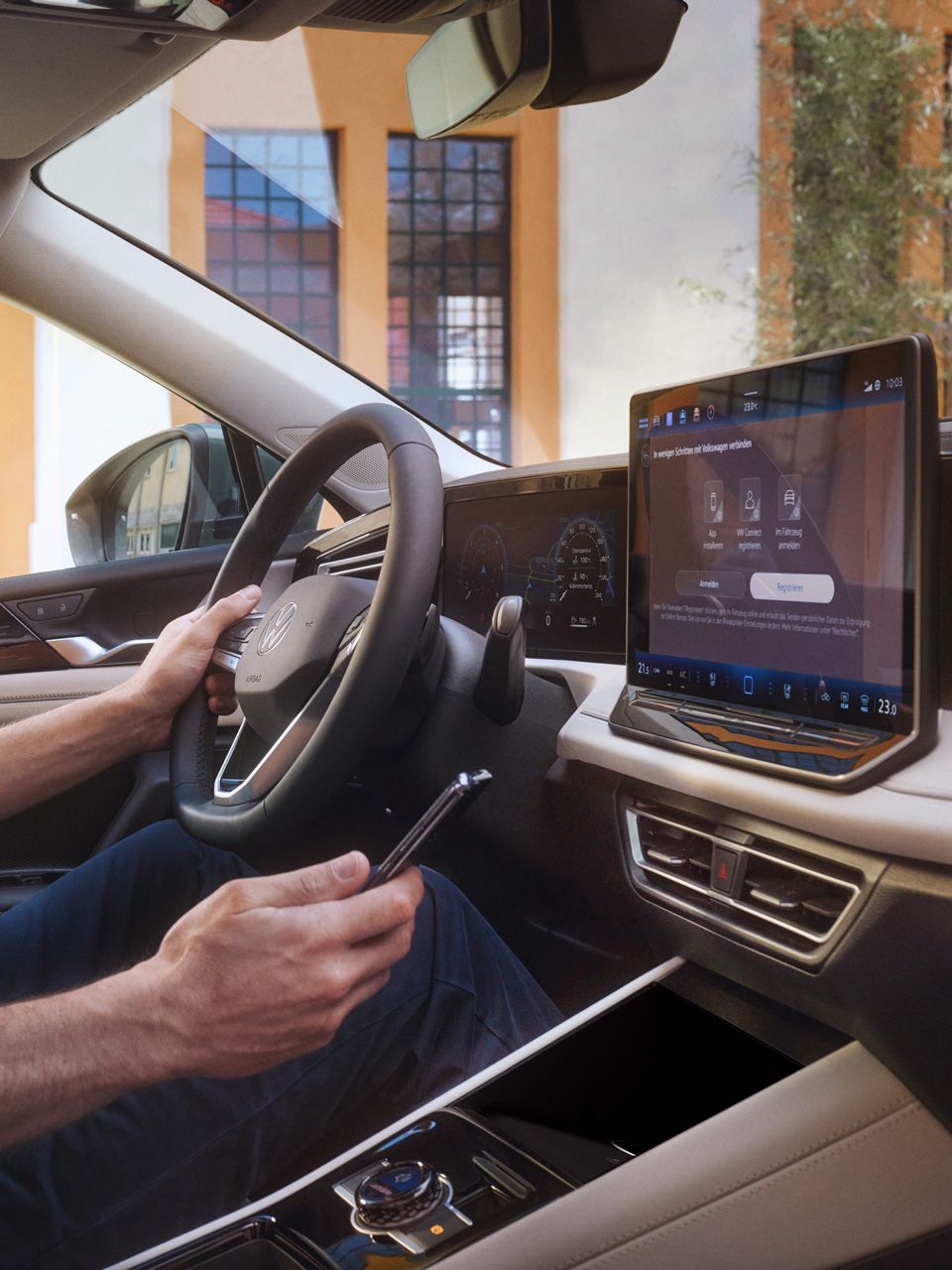 Mann sitzt in VW Tiguan und hält Smartphone in der Hand