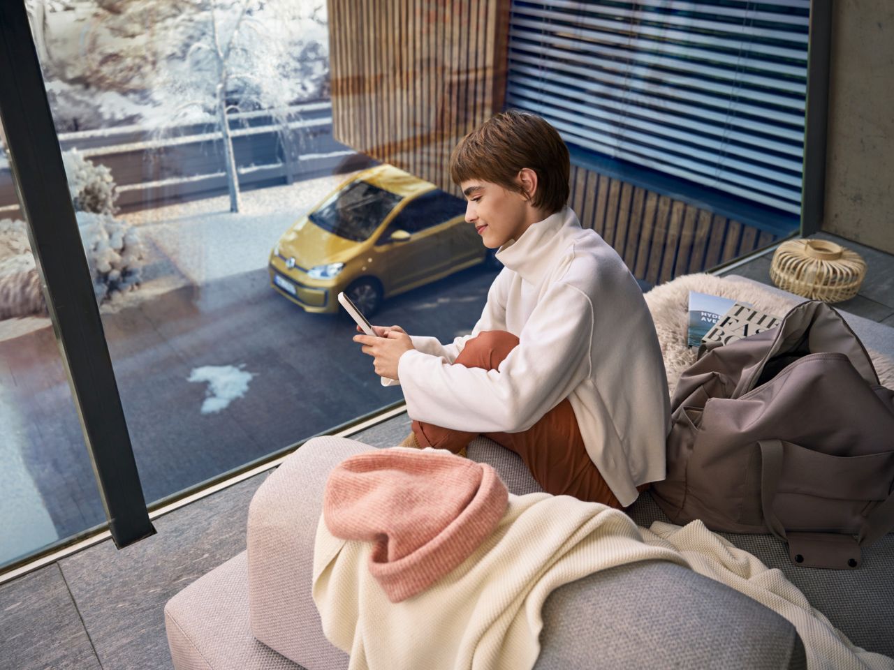 Frau sitzt auf dem Balkon und verbindet sich über das Handy mit ihrem e-up! 