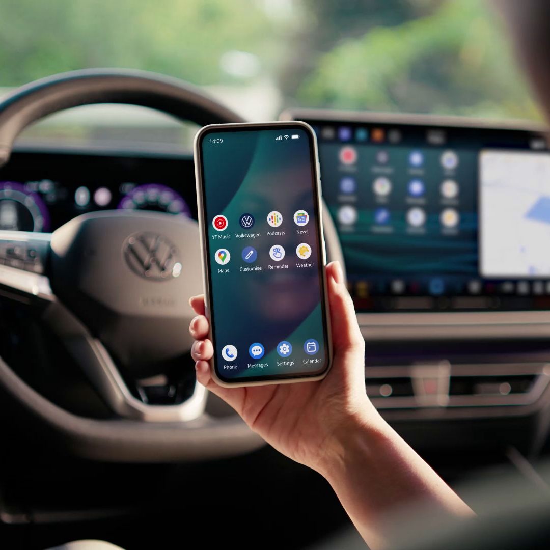 Frau sitzt auf dem Fahrersitz und spiegelt Smartphone per App Connect auf dem Fahrzeugdisplay