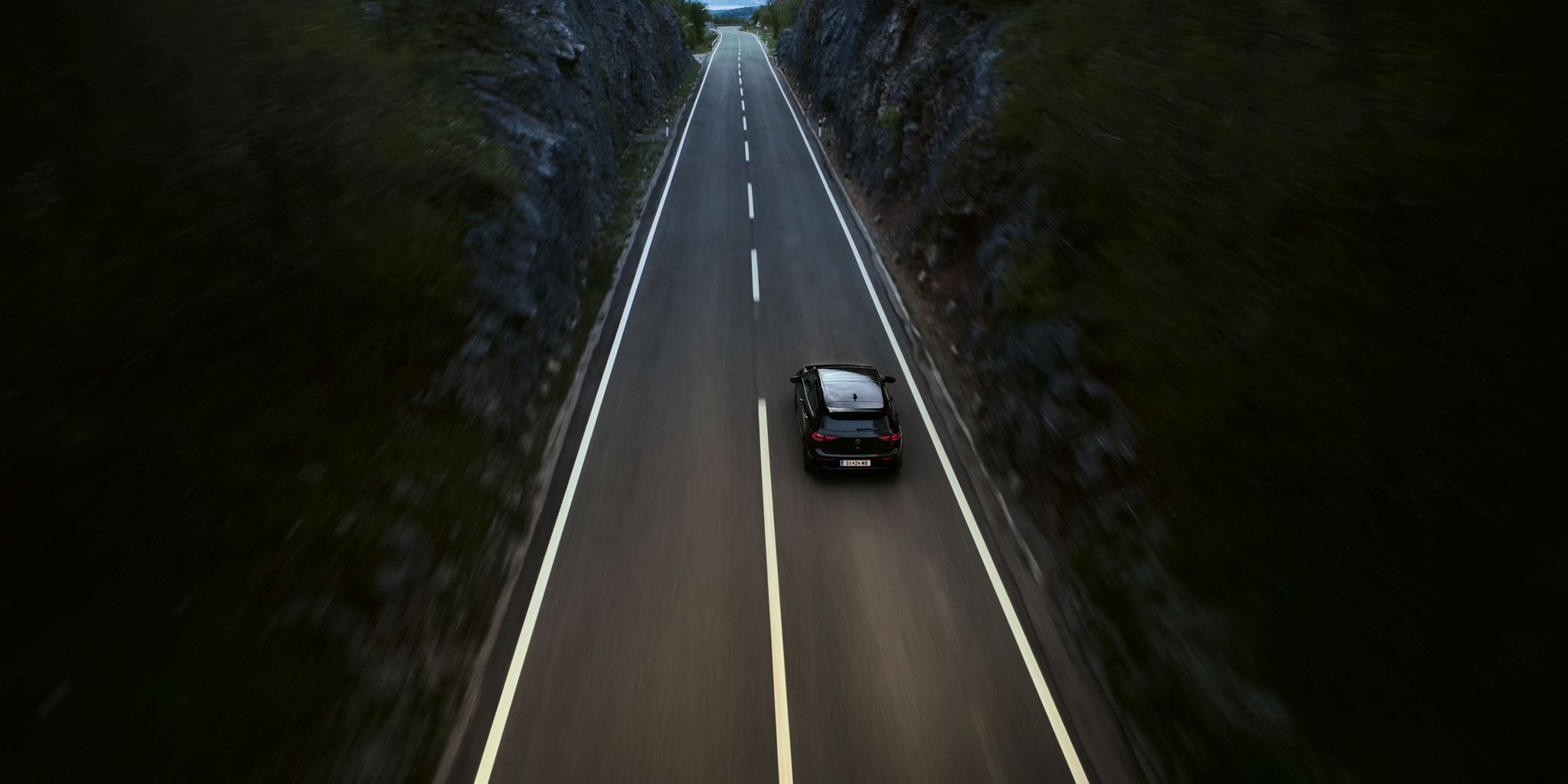 Golf R fährt auf einer Landstraße zwischen zwei Klippen-