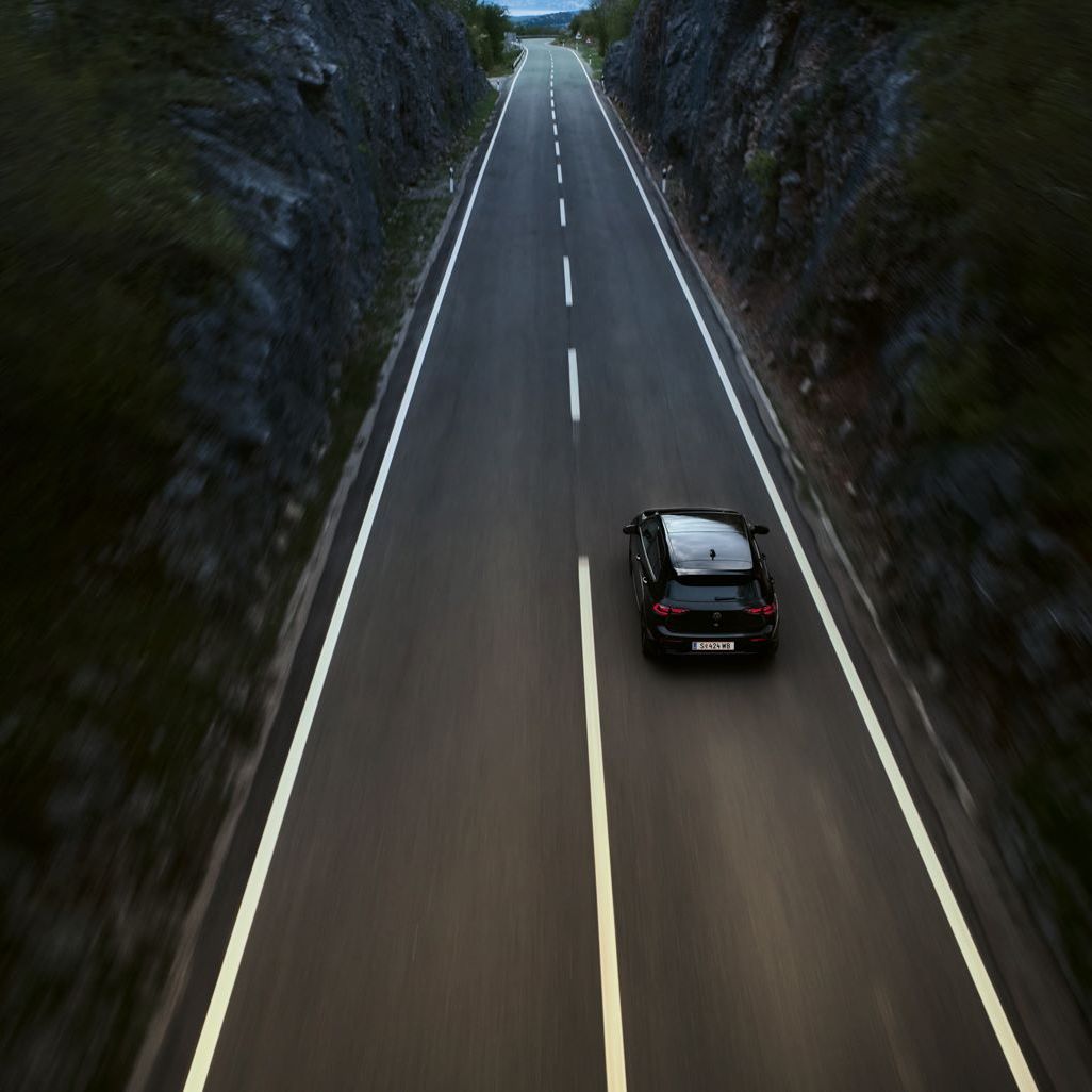 Golf R fährt auf einer Landstraße zwischen zwei Klippen-