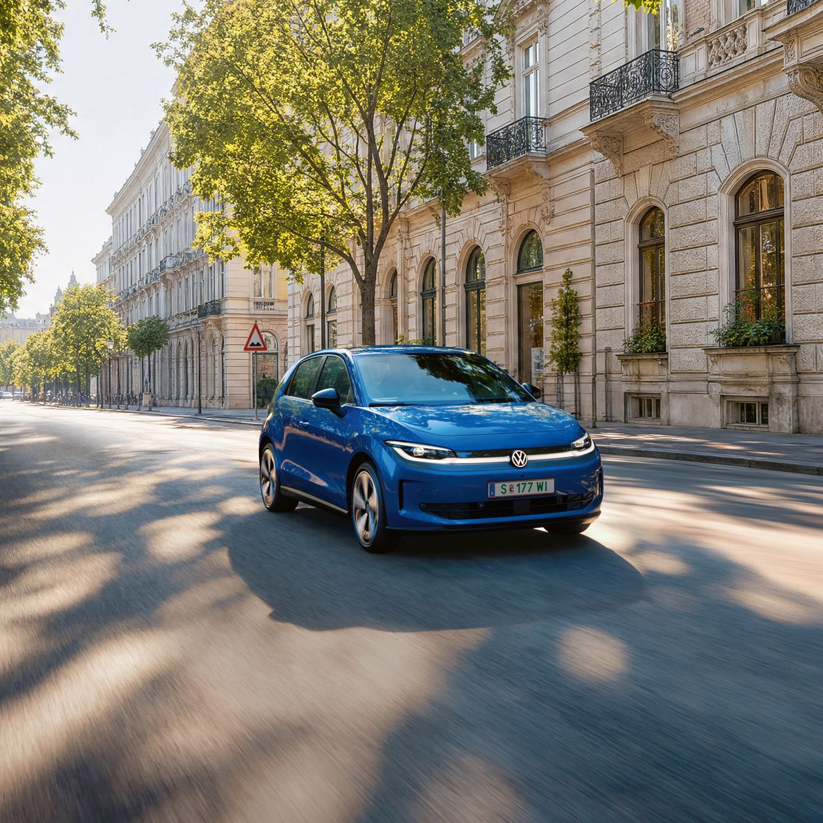 Ein blauer VW ID. Polo fährt auf einer breiten Straße im Schatten einer Allee.