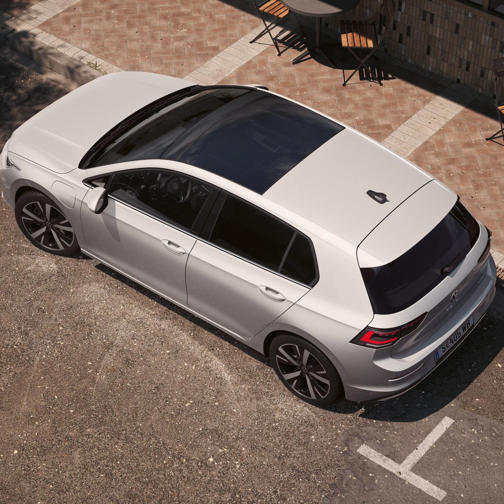 Ein weißer VW Golf eHybrid mit Panoramadach aus der Vogelperspektive, von oben