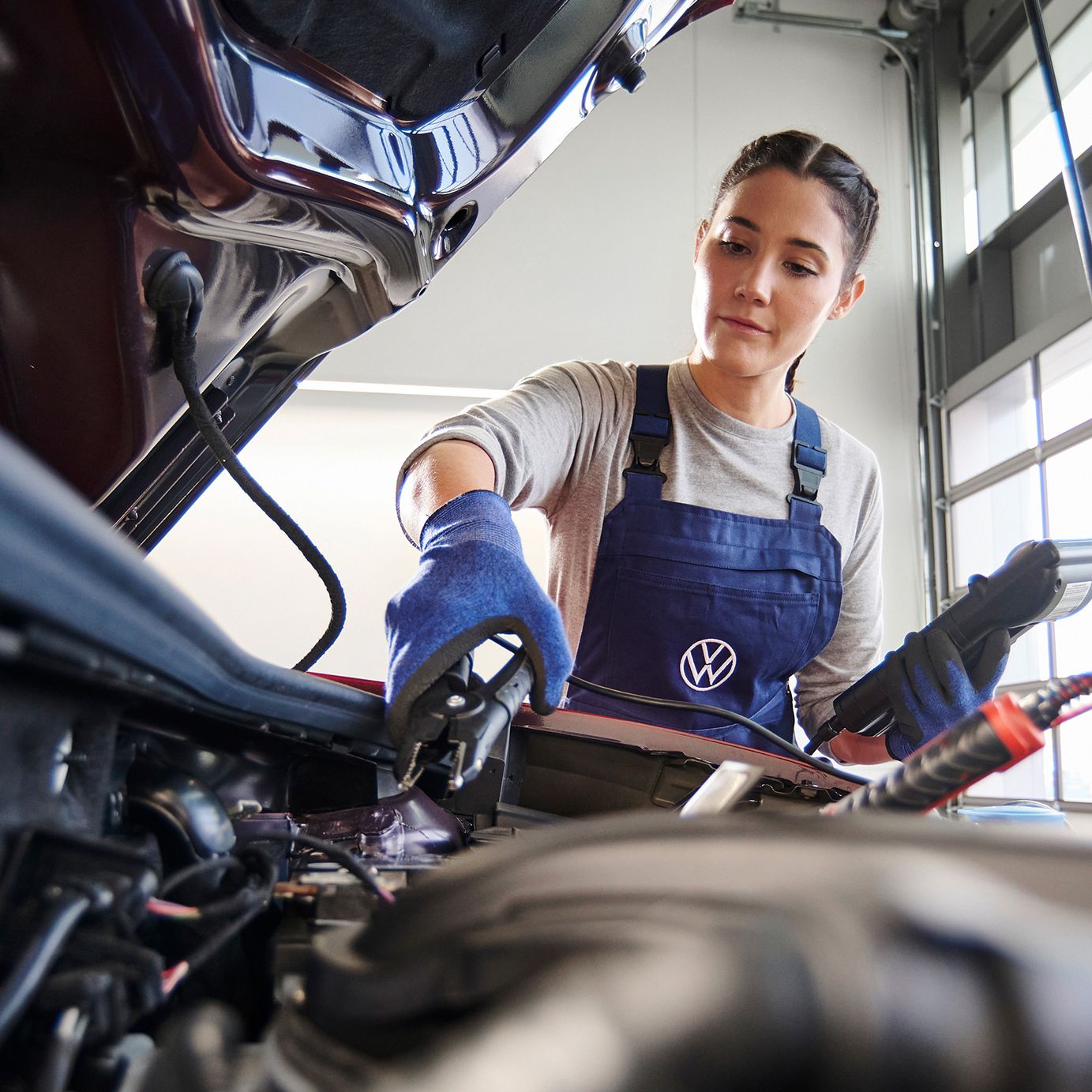 Eine Volkswagen Mechanikerin beim Funktionstest der Starterbatterie.