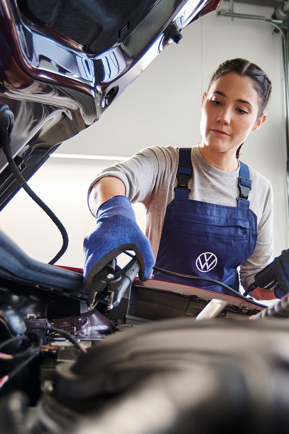 Eine Volkswagen Mechanikerin beim Funktionstest der Starterbatterie.