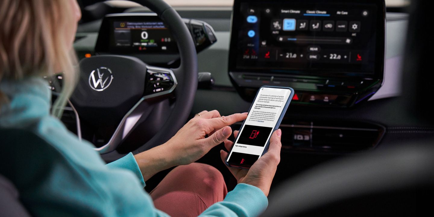 Kundin sitzt am Lenkrad eines VW-Autos und informiert sich über Warnleuchten