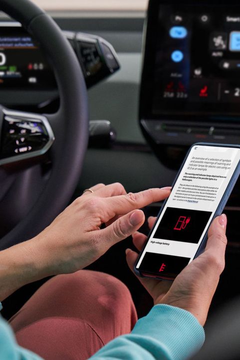 Kundin sitzt am Lenkrad eines VW-Autos und informiert sich über Warnleuchten