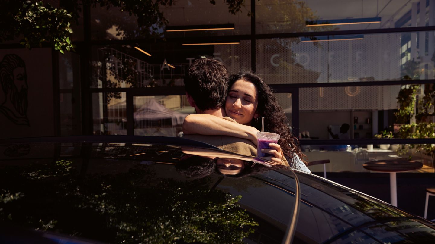 Zwei Personen umarmen sich hinter dem ID.4. 