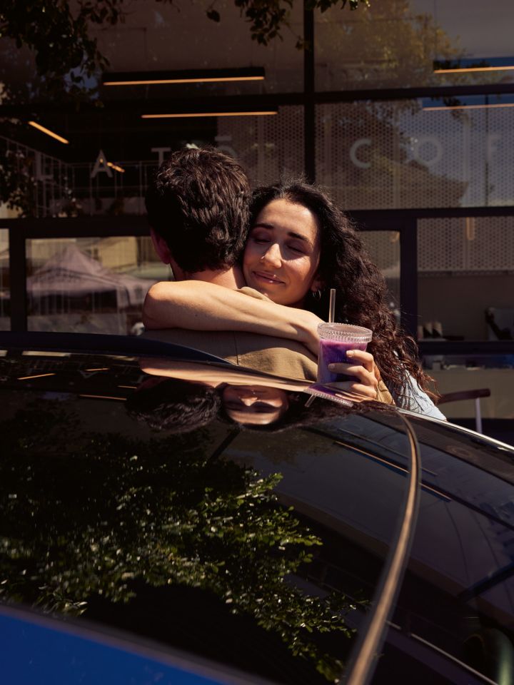 Zwei Personen umarmen sich hinter dem ID.4. 